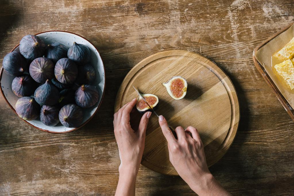 cropped shot of woman cutting fig on rustic wooden table - Photo, Image