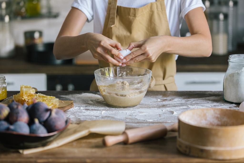 cropped shot of woman breaking egg into bowl during pie preparation - Photo, Image