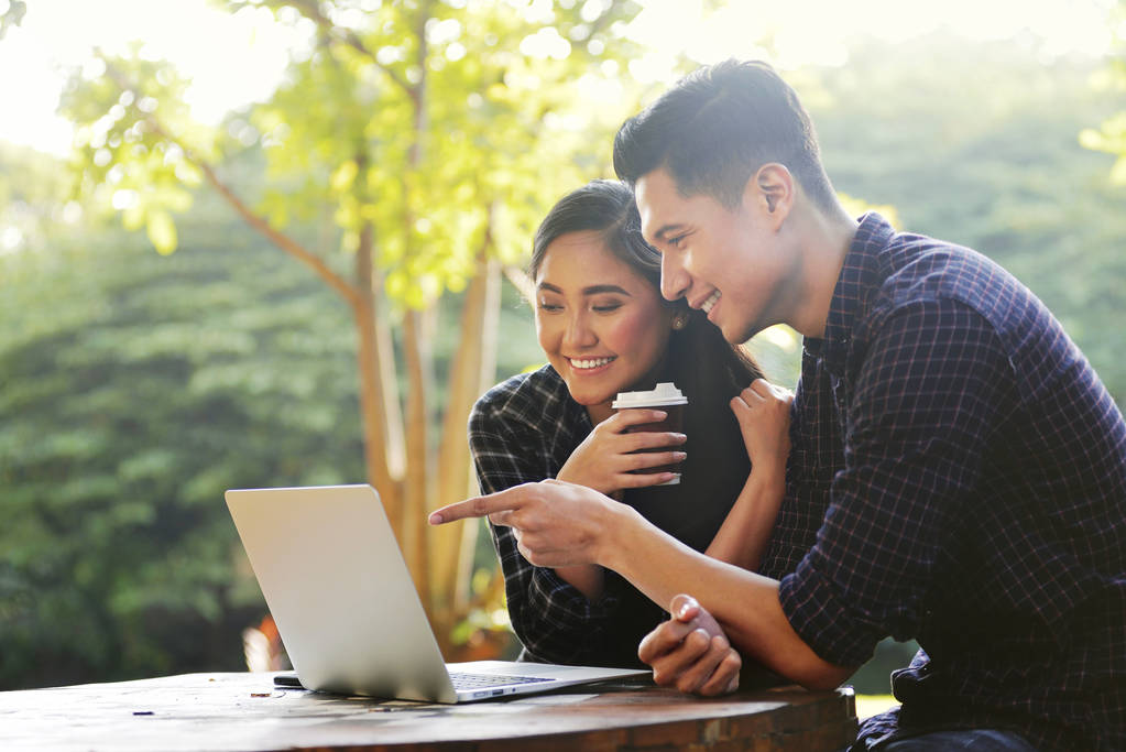 feliz asiático pareja buscando en algo en un portátil en al aire libre
 - Foto, Imagen