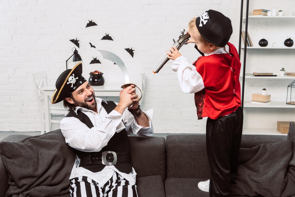 pai e filho em trajes de pirata jogando em casa, conceito de feriado halloween
 - Foto, Imagem