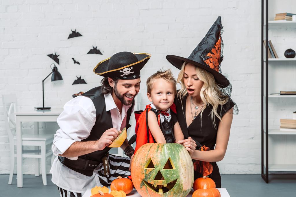 ritratto di genitori e figlio in costumi di Halloween a tavola con zucche a casa
 - Foto, immagini