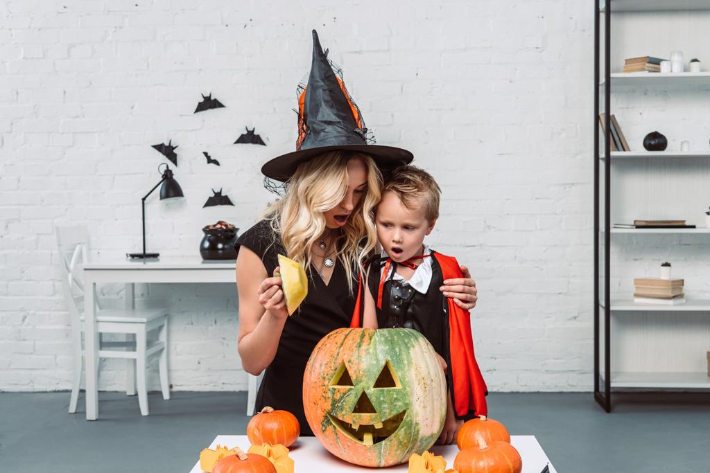 retrato de mãe e filho chocado em trajes de Halloween olhando para a abóbora juntos
 - Foto, Imagem