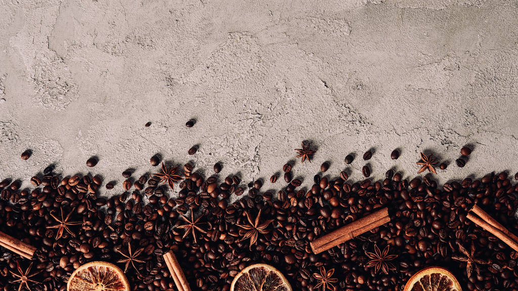 top view of spilled coffee beans with dry spices on concrete surface - Photo, Image