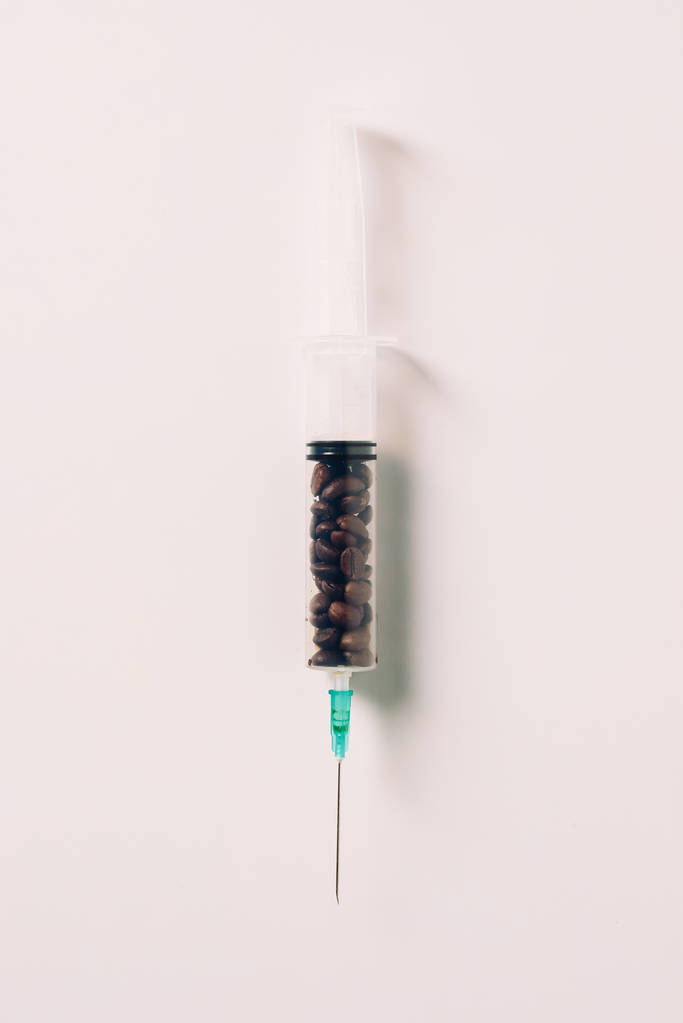 pohled shora stříkačky naplněné kávová zrna na bílý povrch - Fotografie, Obrázek