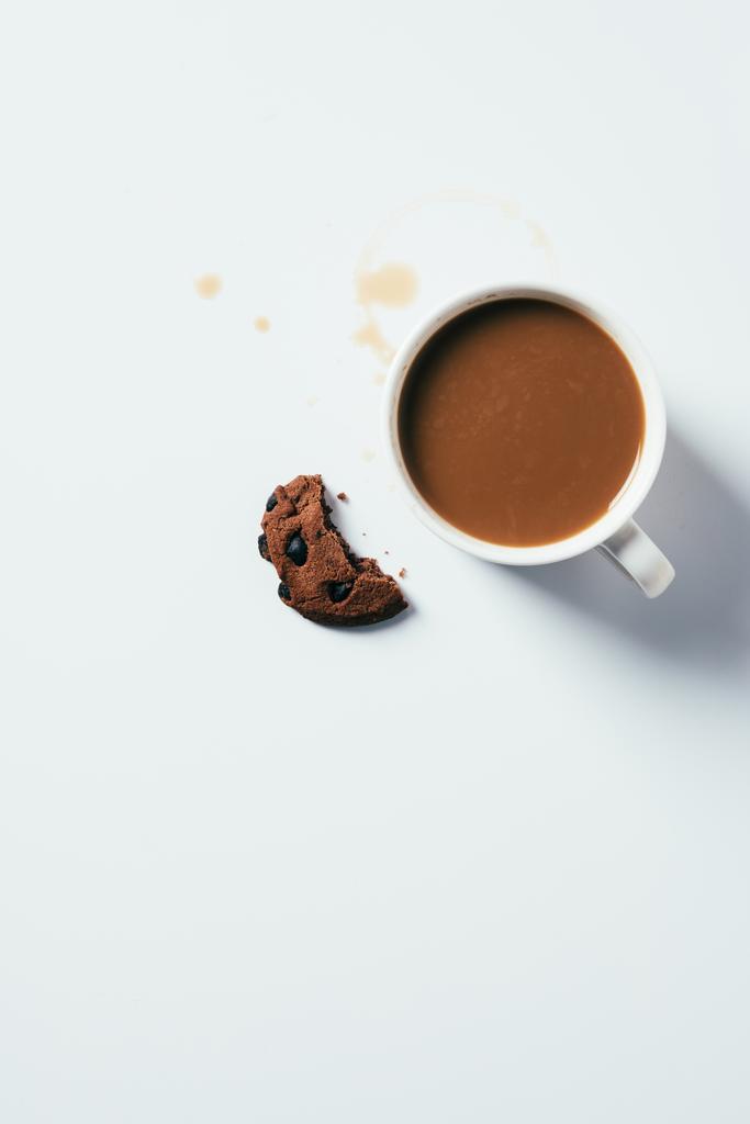вид сверху на чашку кофе с кусочками шоколадного печенья на белой поверхности
 - Фото, изображение