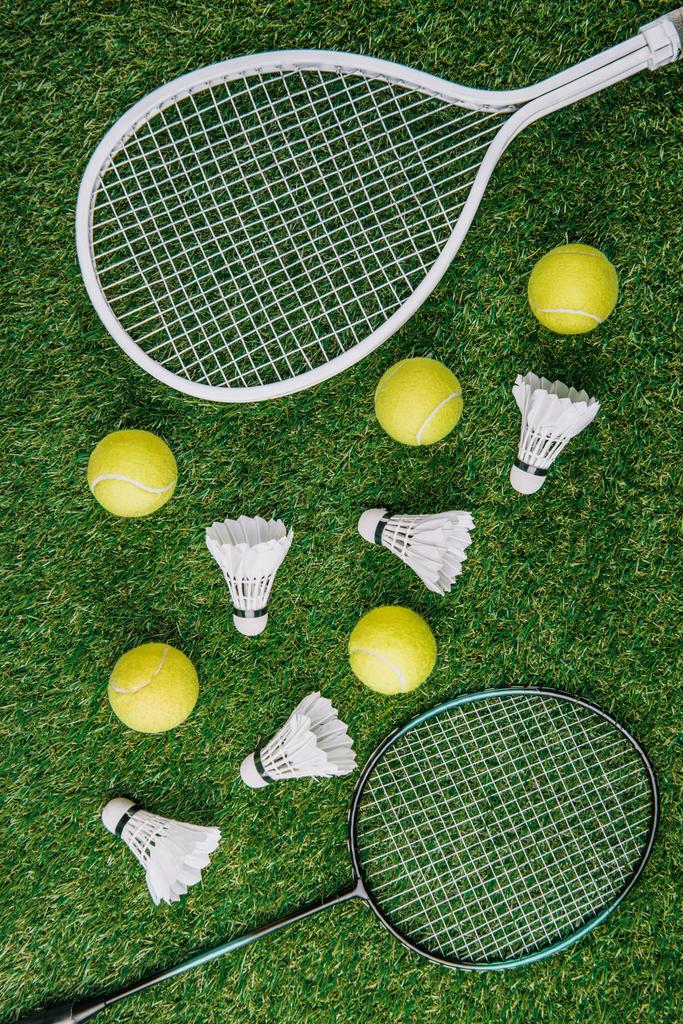 κάτοψη του μπάντμιντον και τένις εξοπλισμός τοποθετημένα στο γκαζόν - Φωτογραφία, εικόνα