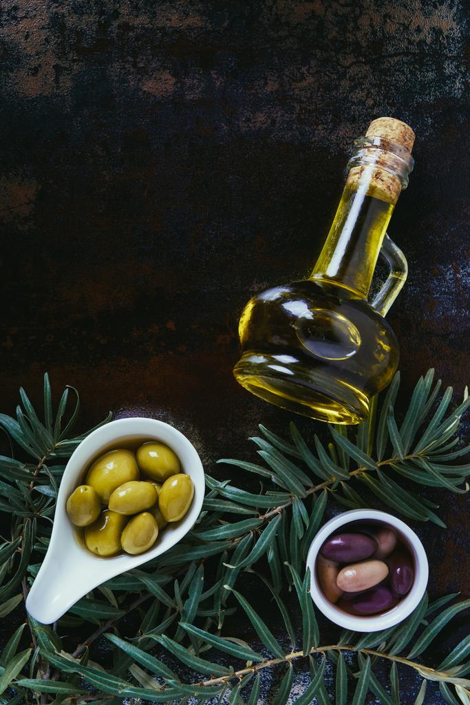 сверху вид вкусных оливок в мисках и бутылках оливкового масла на потрепанной поверхности
 - Фото, изображение