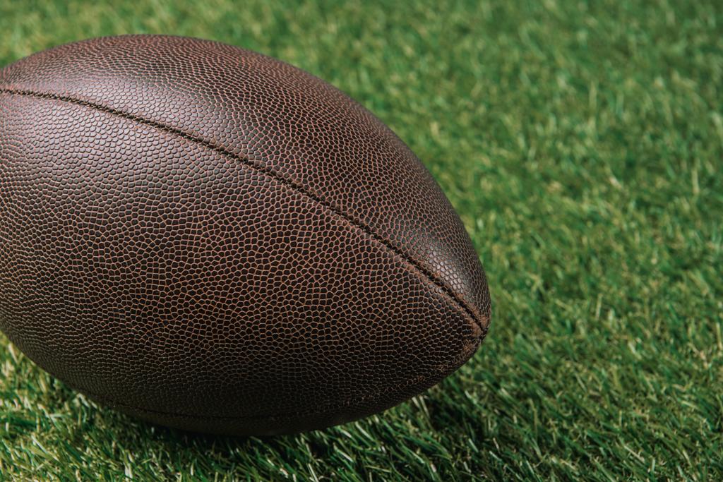 крупним планом шкіряний м'яч регбі лежить на зеленій траві
 - Фото, зображення