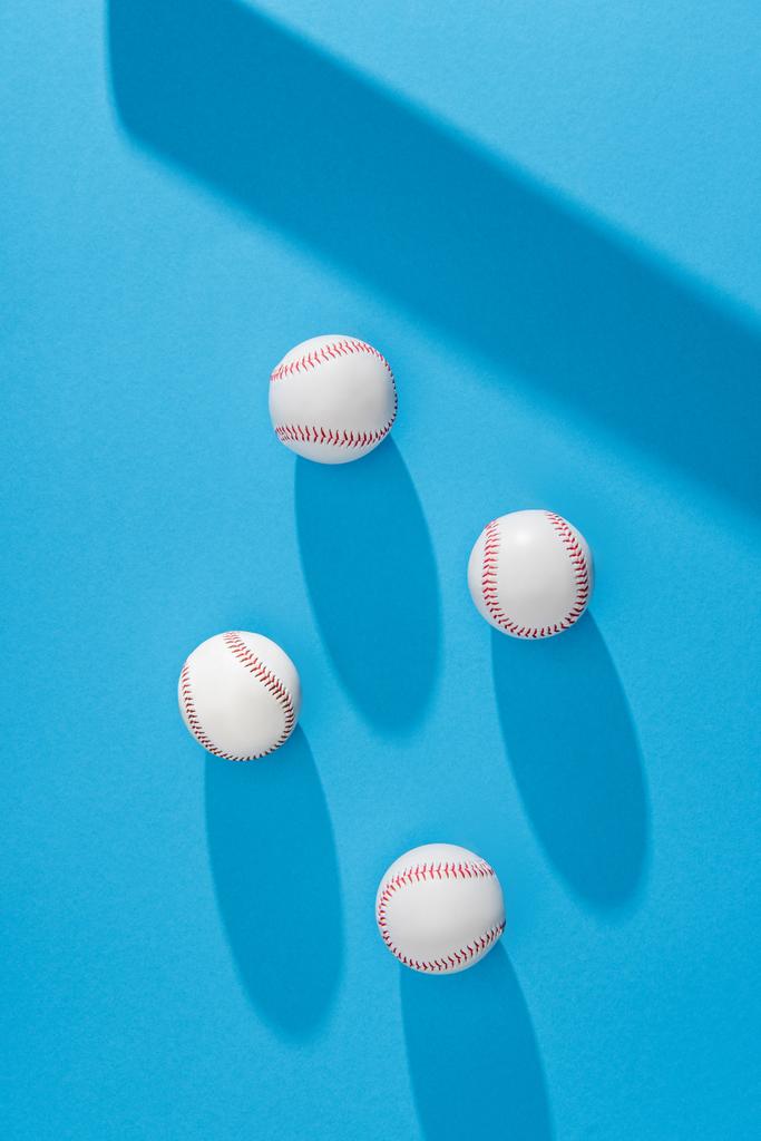 vue de dessus des balles de baseball disposées et de l'ombre de chauve-souris sur fond bleu
 - Photo, image