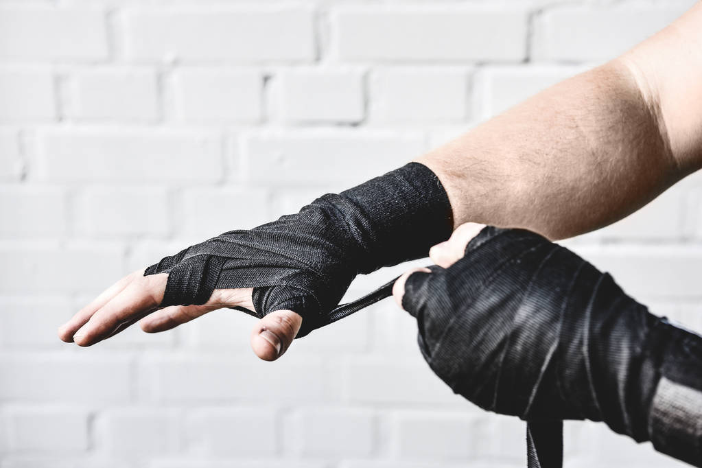 cropped shot of weight lifter wrapping hands before workout in front of white brick wall - Photo, Image