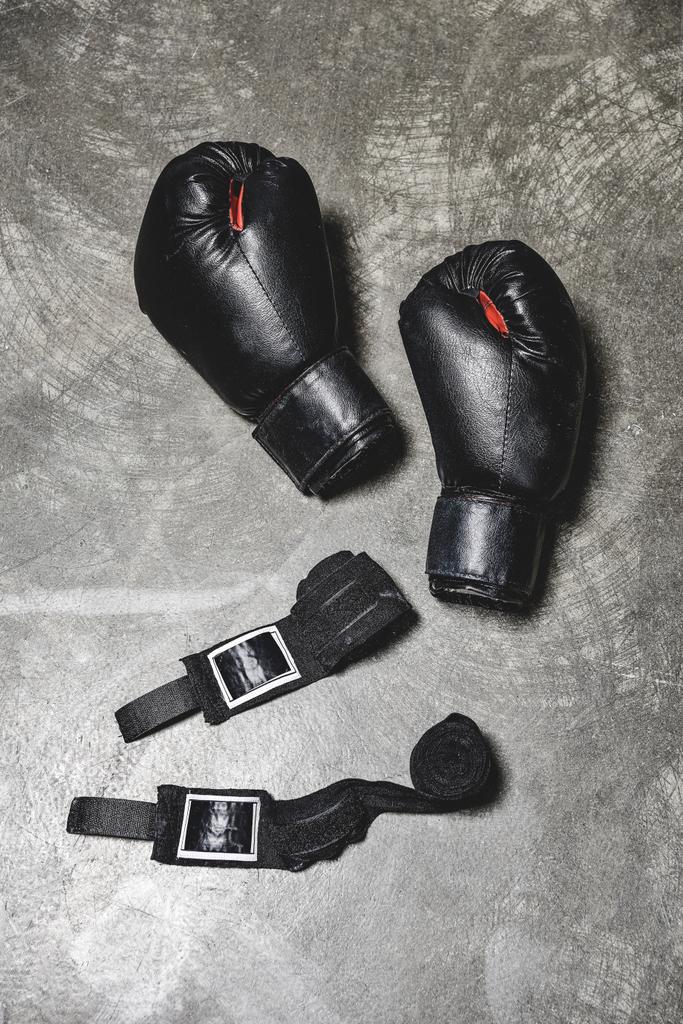 Ansicht von Boxhandschuhen mit Handgelenkbandage, die auf Betonoberfläche liegen - Foto, Bild