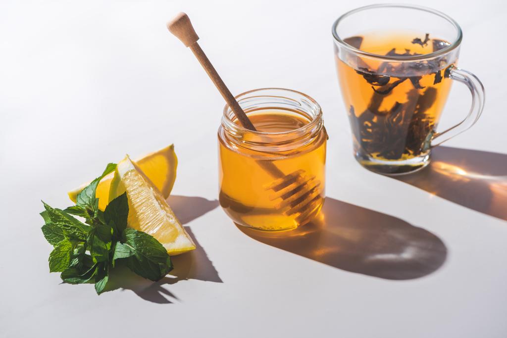 gezonde thee met citroen, munt en honing op wit tafelblad - Foto, afbeelding