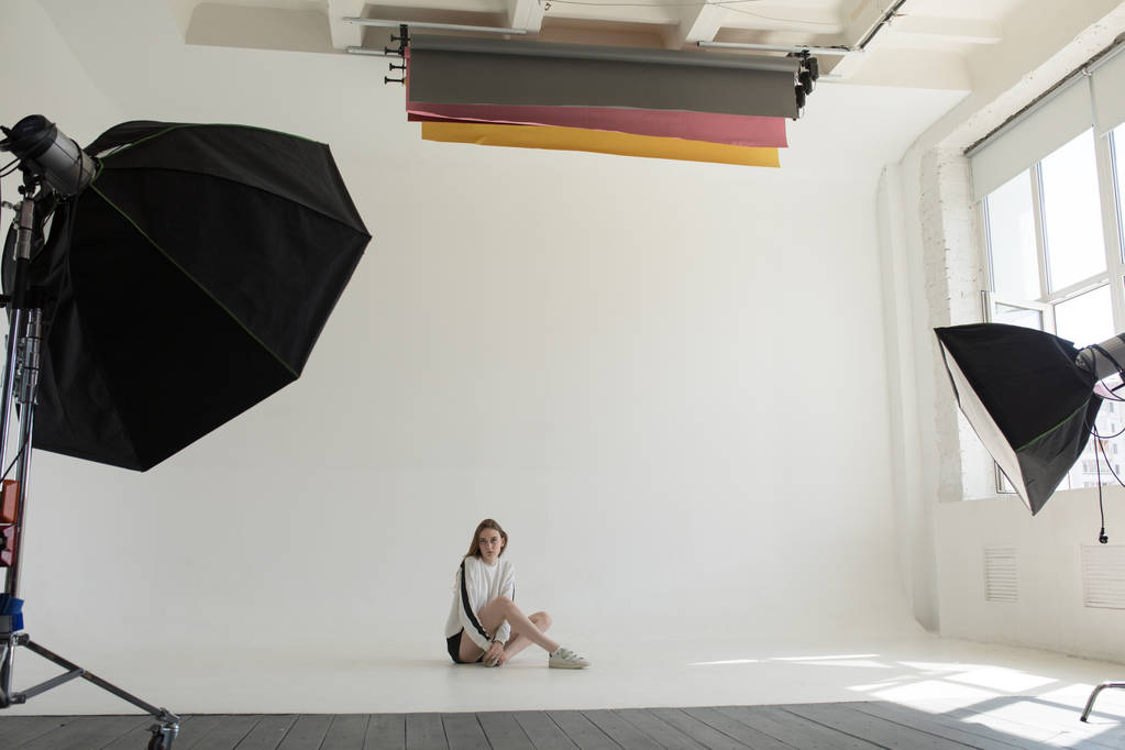 Modelo está sentado e posando em um estúdio de fotografia profissional em um fundo branco
. - Foto, Imagem