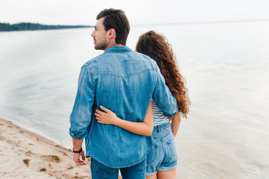 vue arrière du couple embrassant et marchant sur la plage près de la mer
  - Photo, image
