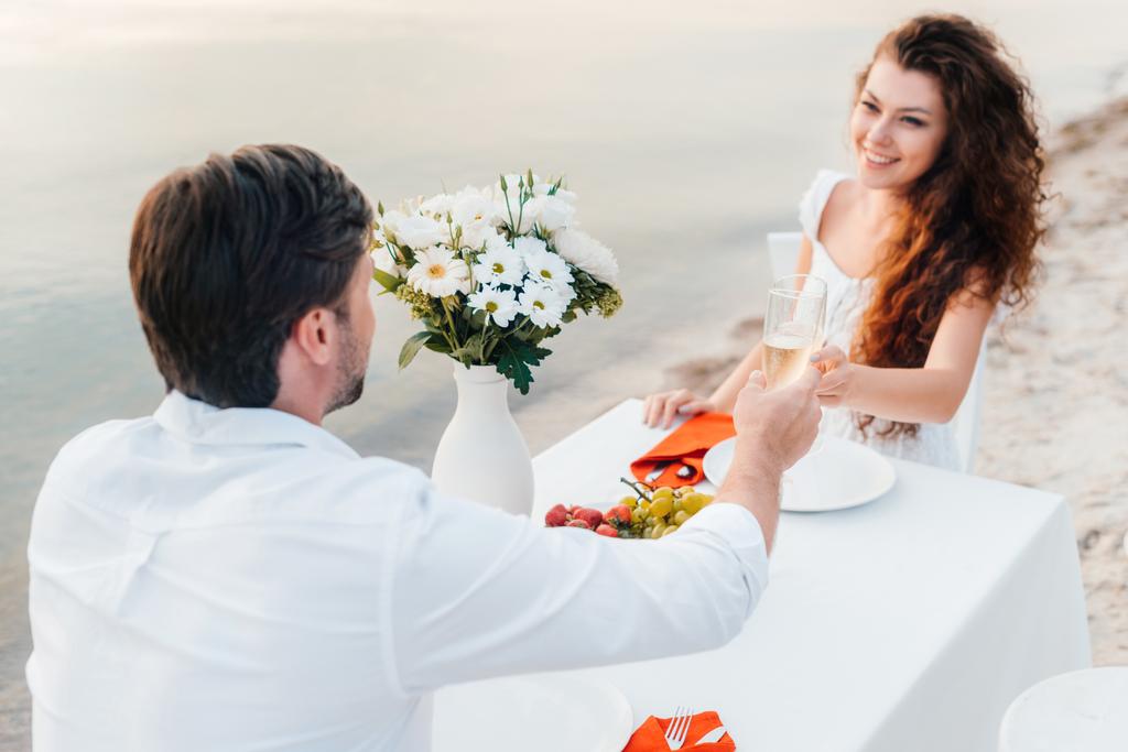 mies ja nainen paahtoleipää samppanjalasien aikana romanttinen päivä rannalla
 - Valokuva, kuva