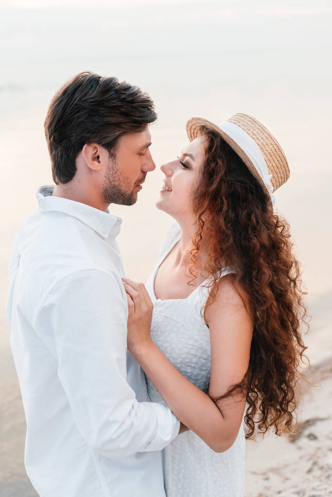 casal feliz olhando um para o outro e abraçando na praia
 - Foto, Imagem