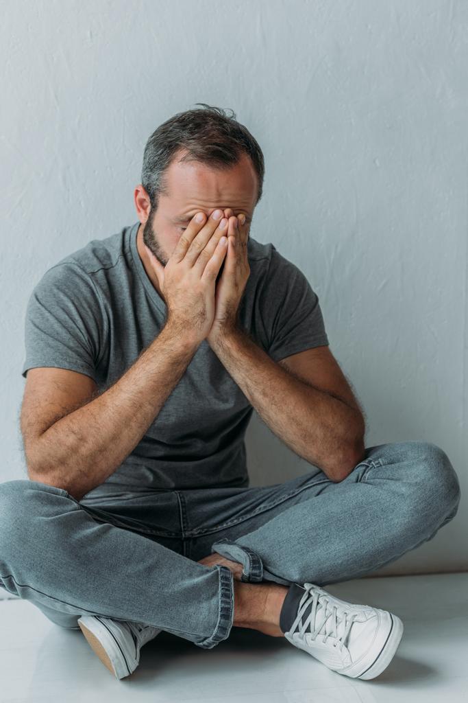 высокий угол обзора стресса мужчины средних лет, сидящего с руками на лице
 - Фото, изображение
