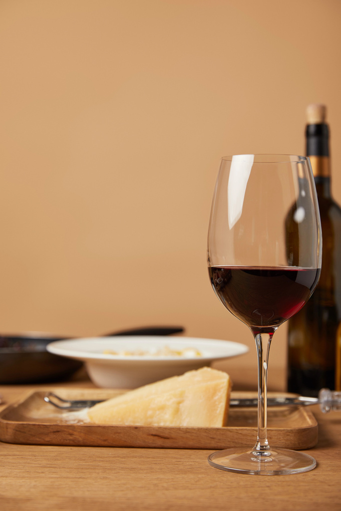 vidro e garrafa de vinho tinto e parmesão ralado para massas na mesa de madeira
 - Foto, Imagem