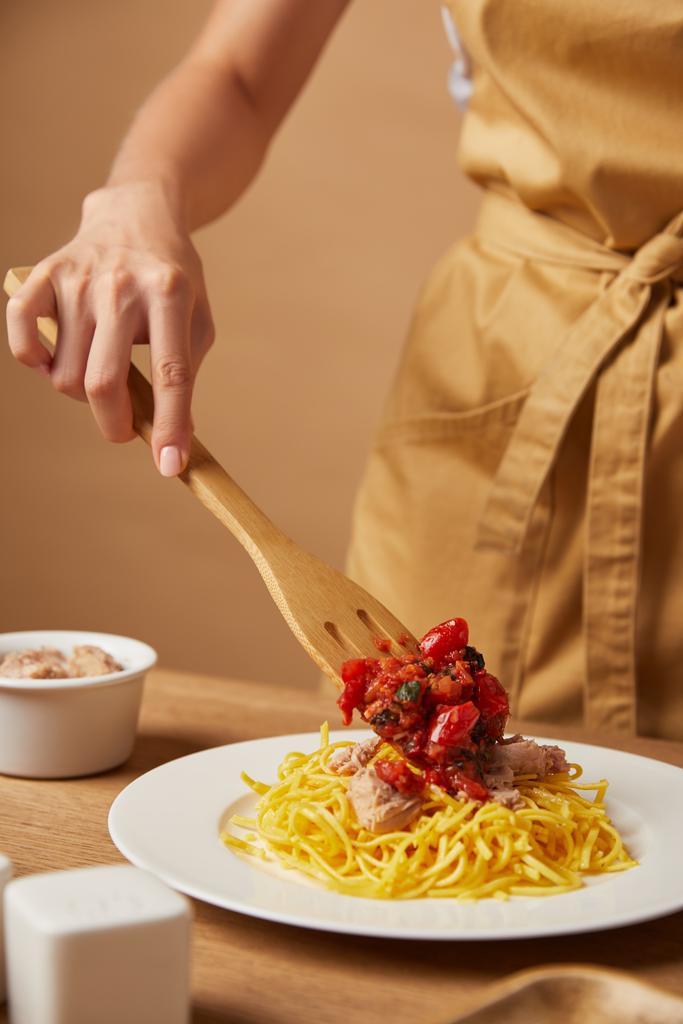 cropped shot of woman putting sauce onto pasta with wooden spatula - Photo, Image