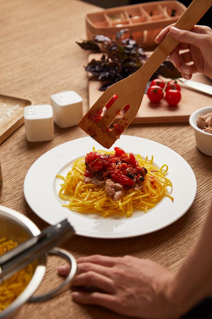 cropped shot of woman putting pasta in plate on wooden table - Photo, Image