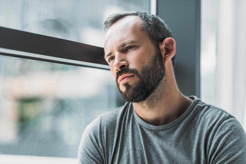 frustrated bearded man leaning at window and looking away - Photo, Image