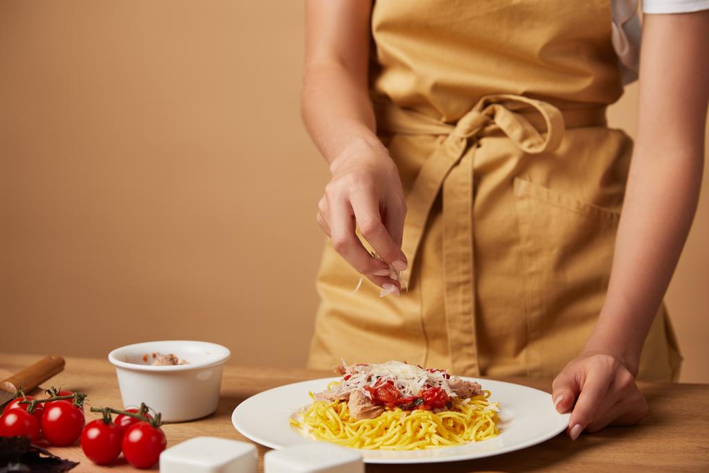 tiro recortado de la mujer derramando queso rallado en la pasta en el plato
 - Foto, imagen