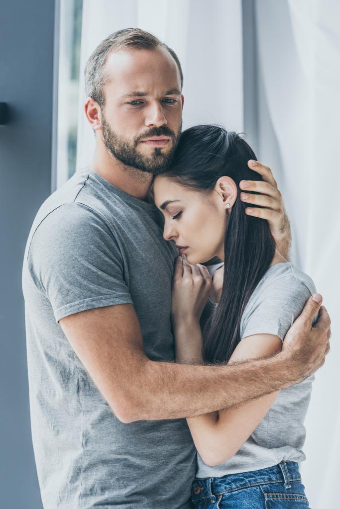 boos bebaarde man knuffelen en het ondersteunen van depressieve jonge vrouw - Foto, afbeelding