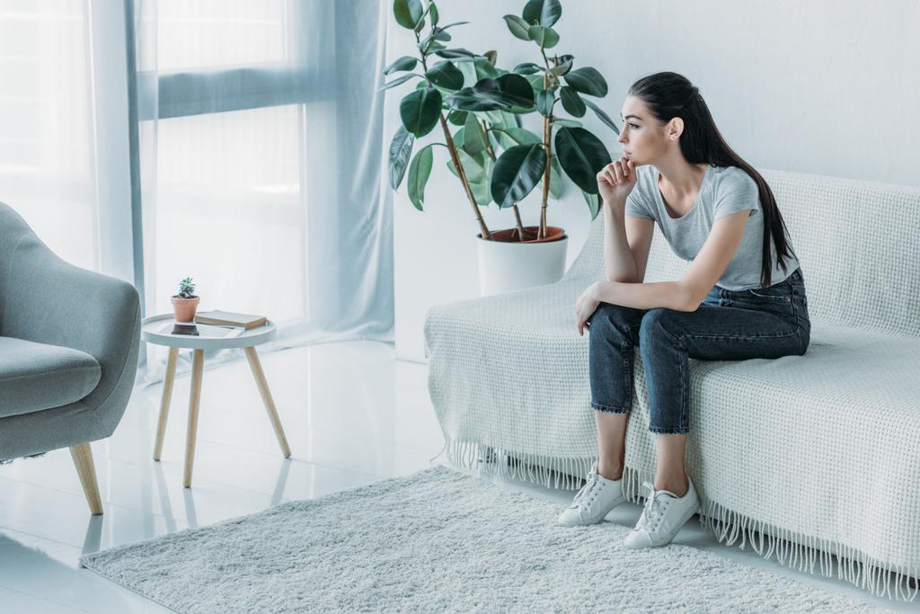 Blick aus der Vogelperspektive auf eine traurige junge Frau in Depressionen, die auf dem Sofa sitzt und zu Hause wegschaut - Foto, Bild