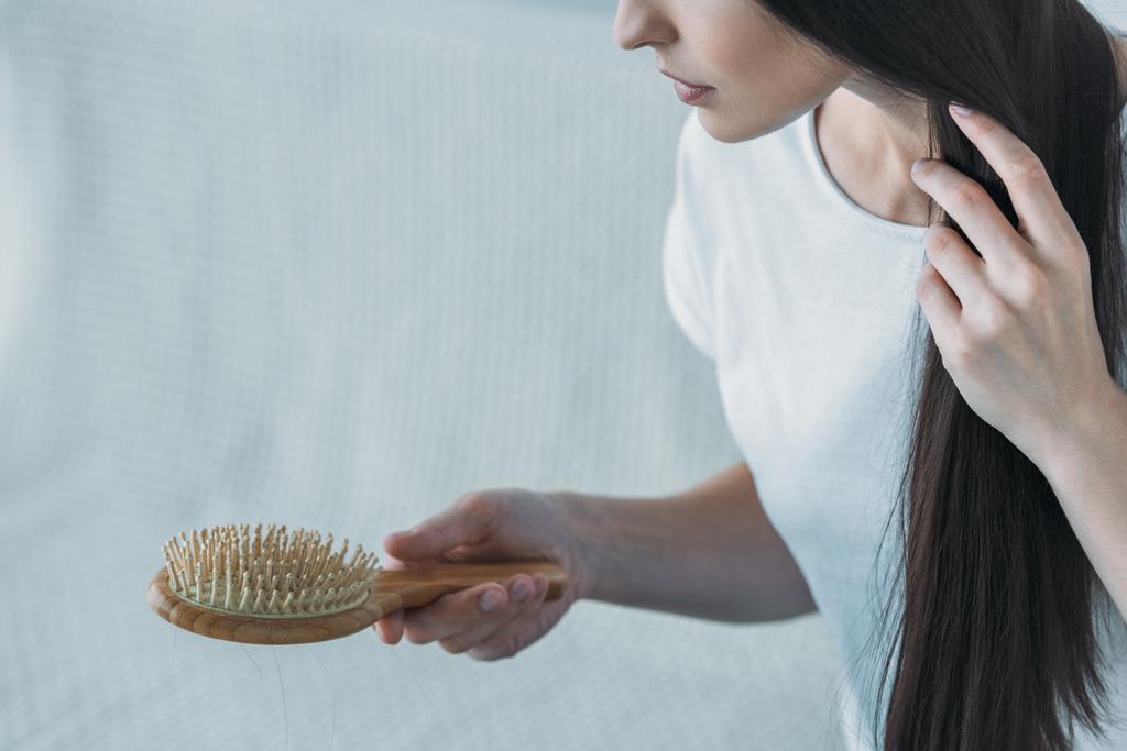 abgeschnittene Aufnahme einer traurigen brünetten Frau mit Haarbürste, Haarausfall-Konzept - Foto, Bild