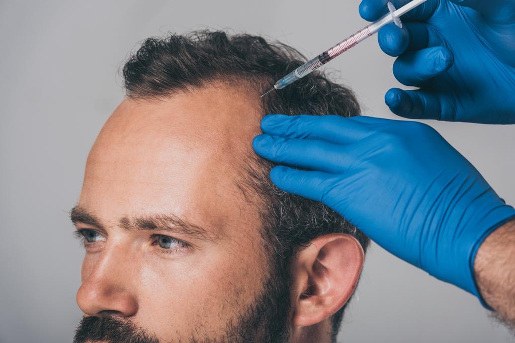 oříznuté shot lékaře s injekční stříkačkou dát injekci na člověka s alopecie izolované Grey   - Fotografie, Obrázek