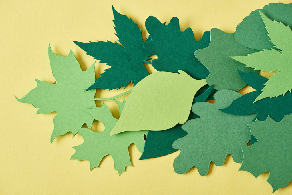 plnoformátový zelené ručně vyřezávaného listoví a uspořádány na žlutém pozadí - Fotografie, Obrázek