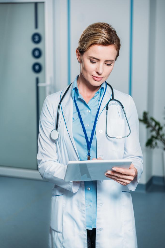 доросла жінка-лікар зі стетоскопом над шиєю за допомогою цифрового планшета в лікарні
  - Фото, зображення
