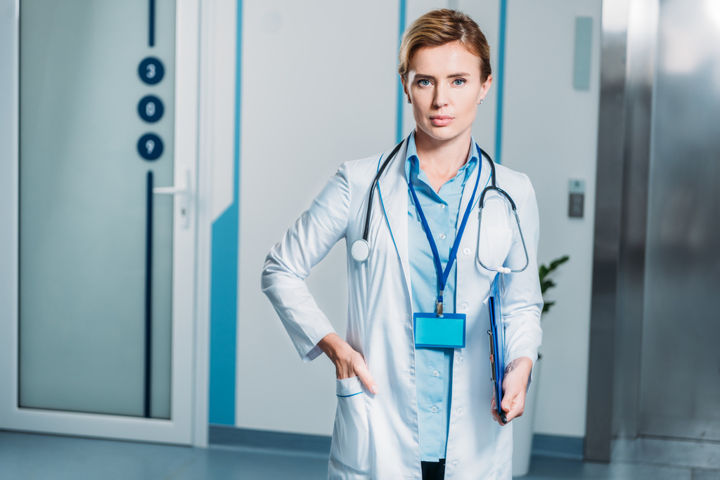 портрет женщины-врача со стетоскопом над шеей, держащей планшет в больнице
  - Фото, изображение