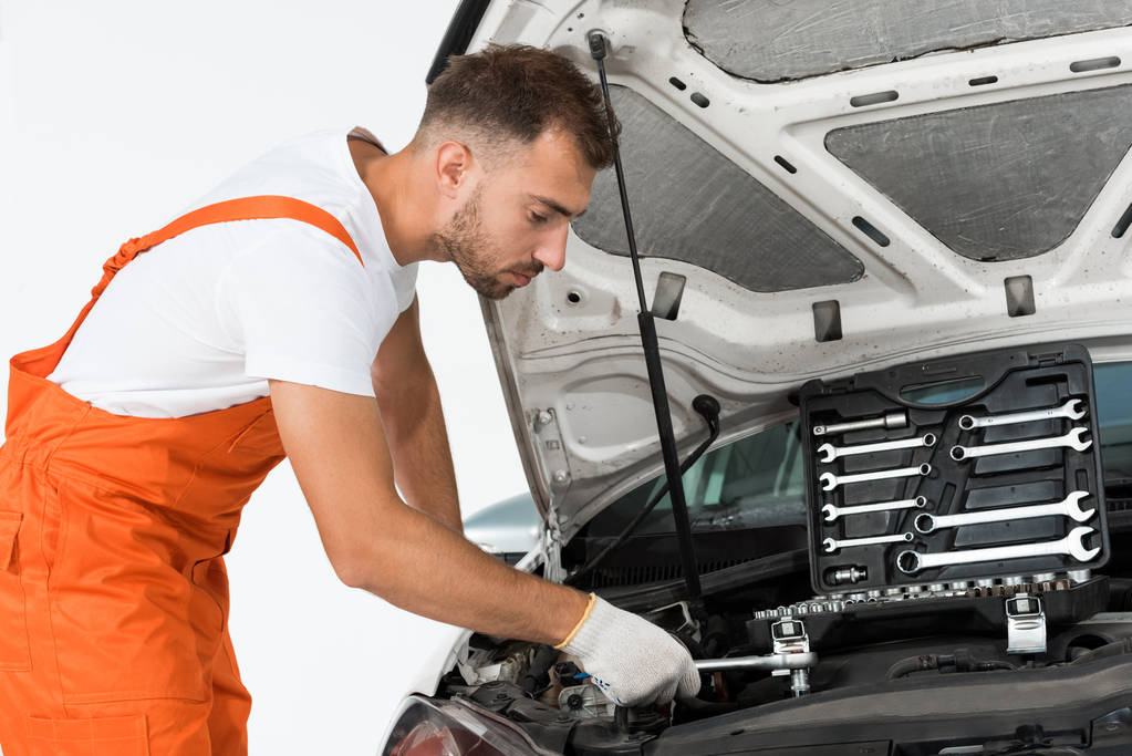 side view of handsome auto mechanic auto mechanic fixing car with wrench on white - Photo, Image