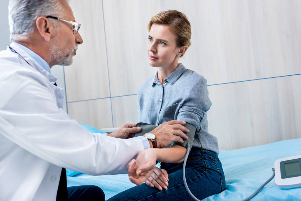 Reifer männlicher Arzt misst Druck einer Patientin mit Tonometer im Krankenhauszimmer - Foto, Bild