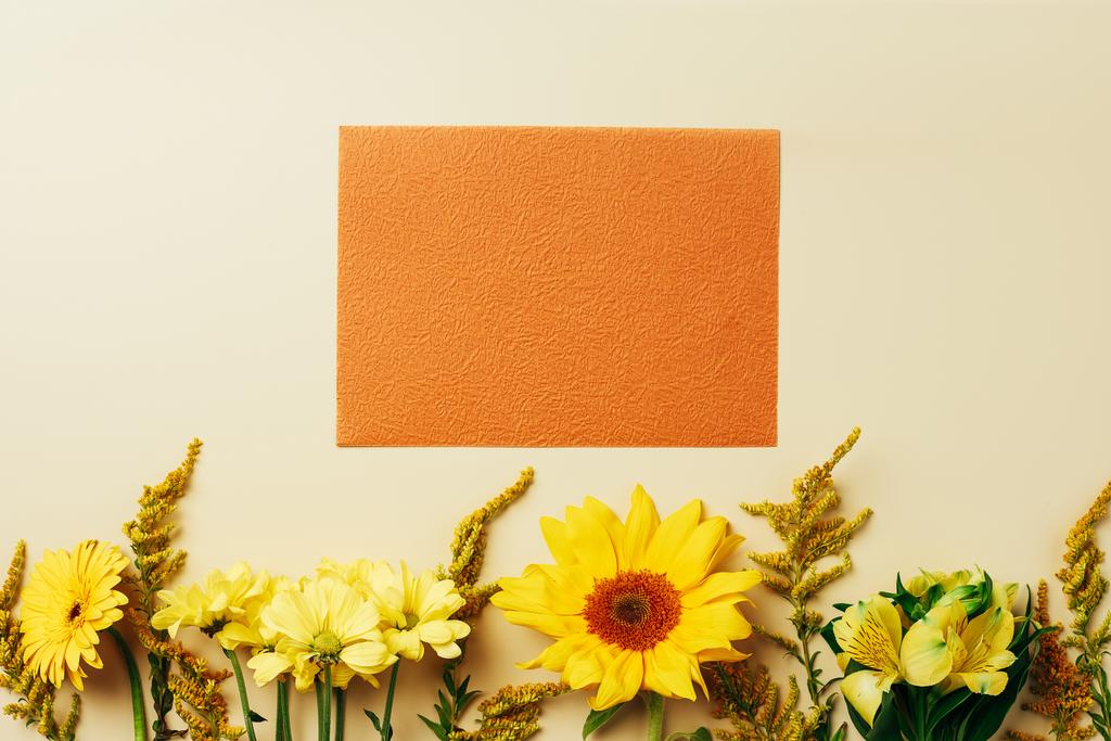 plano con hermosas flores y disposición de la tarjeta naranja vacía sobre fondo beige
 - Foto, Imagen