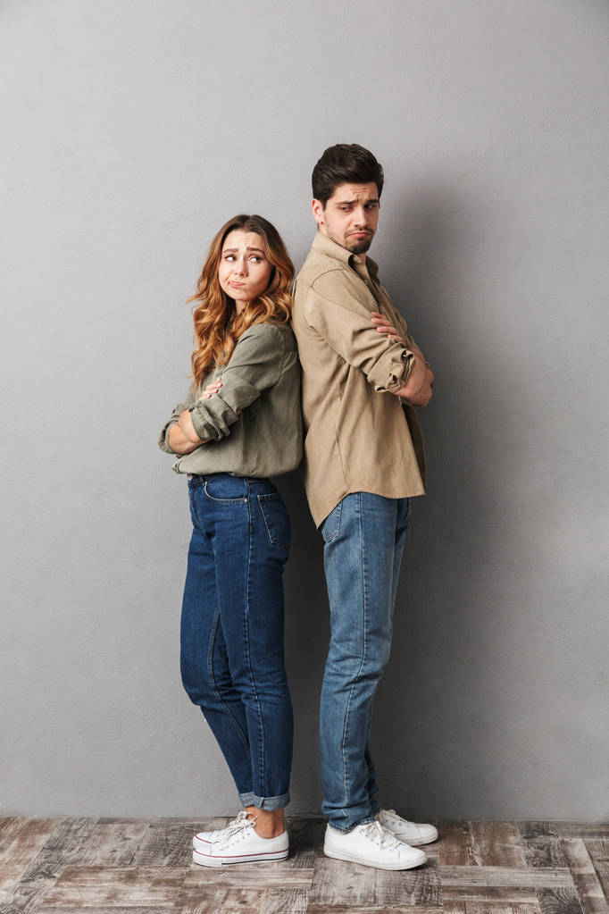 Ritratto a figura intera di una giovane coppia triste in piedi schiena contro schiena con le braccia incrociate isolate sul grigio
 - Foto, immagini