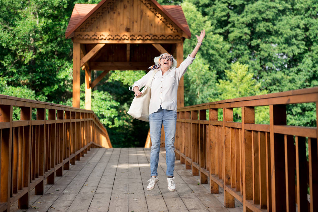 Onnellinen eläkkeellä nainen hyppäämällä nauttien mukava ekomatkailu
 - Valokuva, kuva