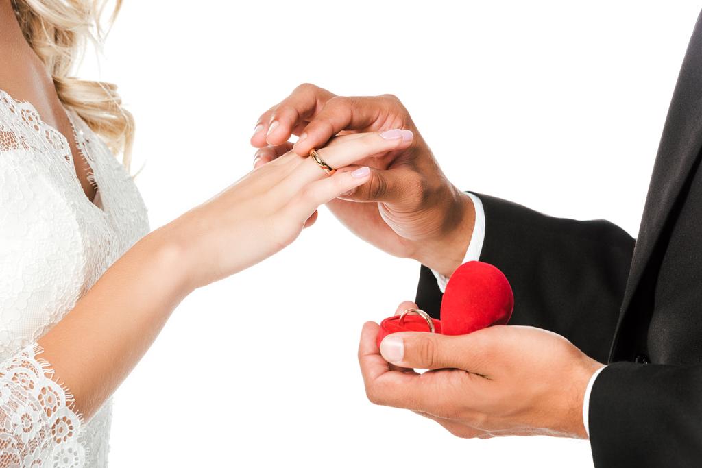περικοπεί shot του γαμπρού βάζοντας στο γαμήλιο δαχτυλίδι στο δάχτυλο νύφες που απομονώνονται σε λευκό - Φωτογραφία, εικόνα