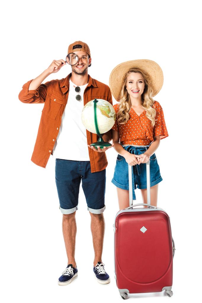 casal sorrindo em pé com lupa, globo e saco de viagem isolado no branco
 - Foto, Imagem
