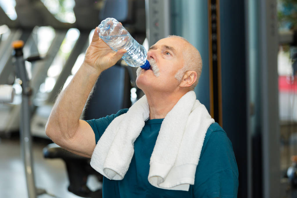 homem sênior bebendo de garrafa de água na sala de ginásio
 - Foto, Imagem