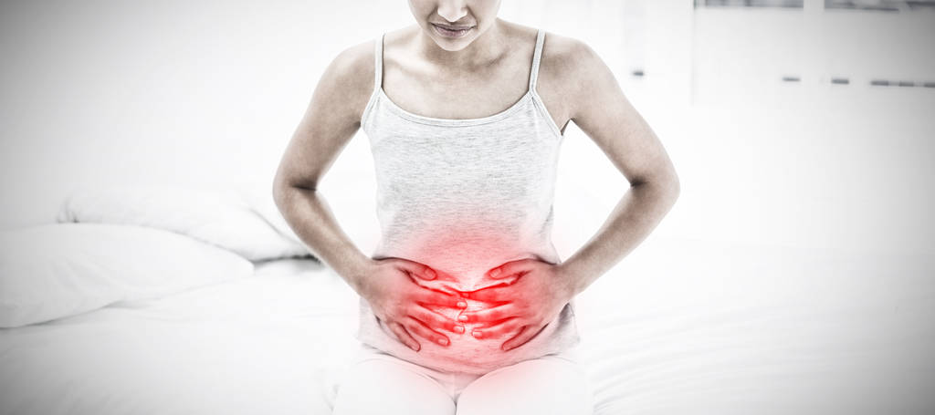 Casual γυναίκα με πόνο στο στομάχι κάθεται στο κρεβάτι κατά επισημασμένο πόνου - Φωτογραφία, εικόνα