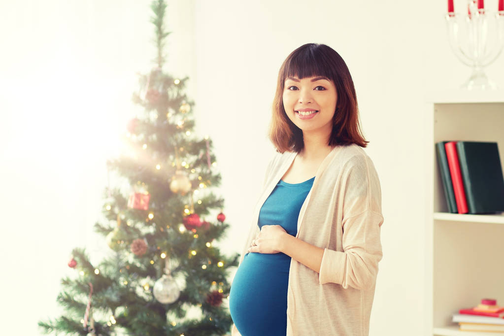 ευτυχισμένος έγκυος γυναίκα στο χριστουγεννιάτικο δέντρο στο σπίτι - Φωτογραφία, εικόνα