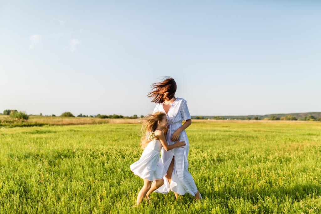 母と娘で一緒に楽しんで、風の強い日に緑の牧草地で受け入れ - 写真・画像