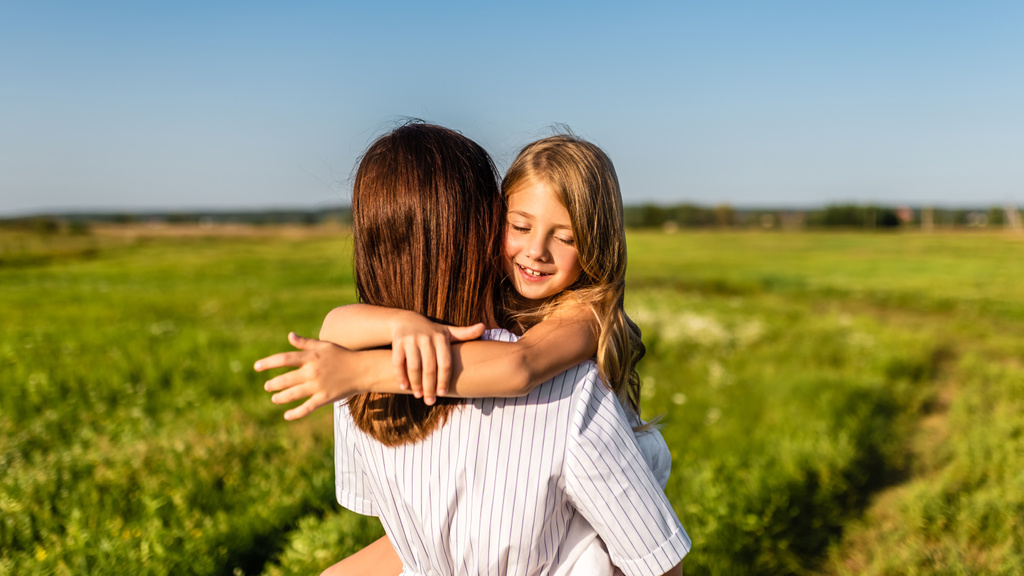 緑の牧草地の幸せな娘を抱く母親 - 写真・画像