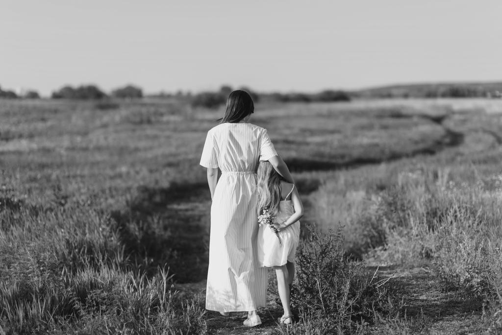 czarno-białe zdjęcie matka i córka chodzenie przy wiejskiej drodze, w zielony łąka - Zdjęcie, obraz