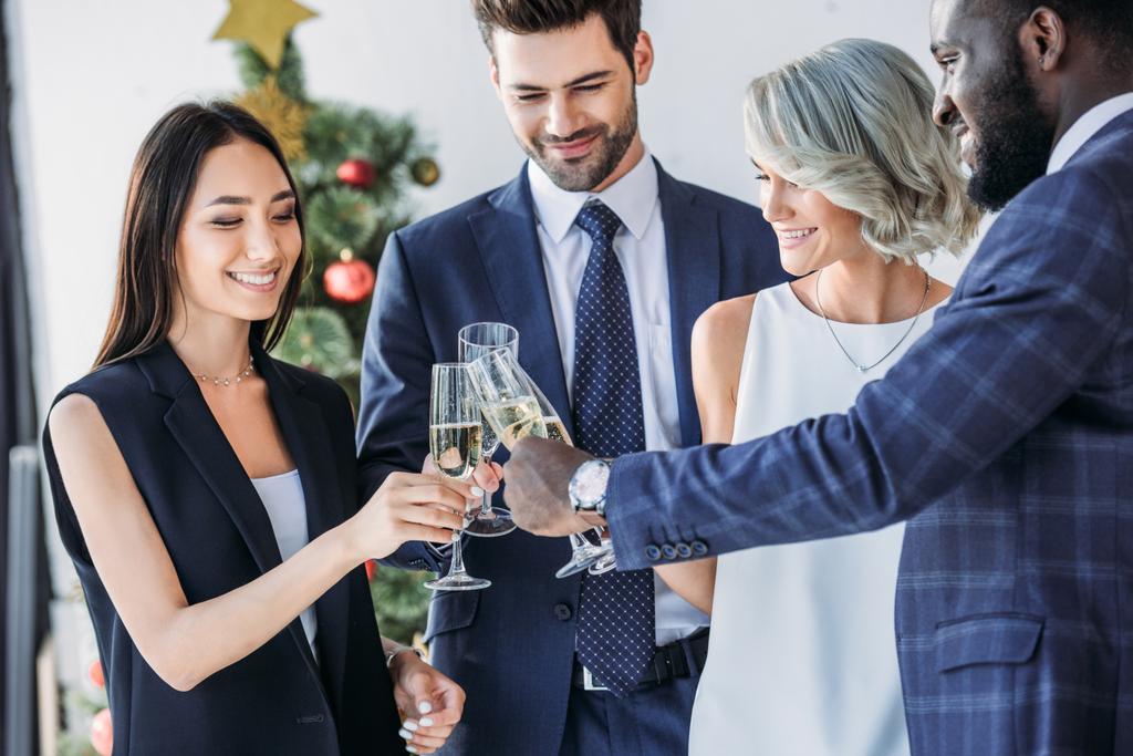 empresarios multiétnicos tintinean con copas de champán con árbol de Navidad en el fondo en la oficina
 - Foto, imagen