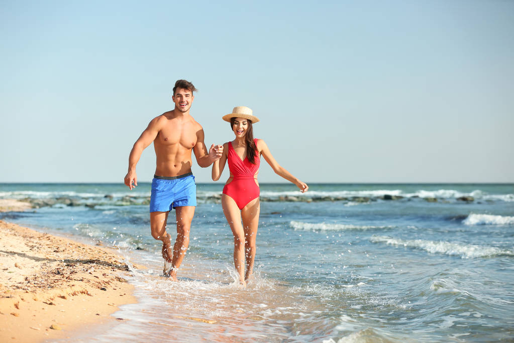 Šťastný mladý pár baví na pláži slunečného dne - Fotografie, Obrázek