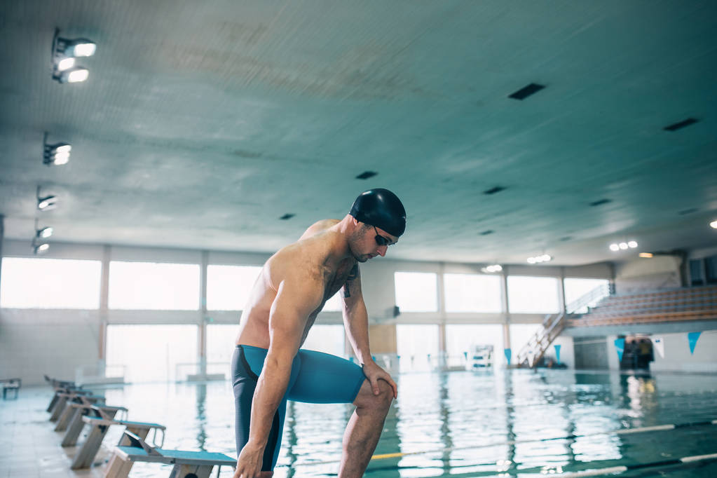 Een jonge sportieve zwemmer voorbereiden om te springen in het zwembad. - Foto, afbeelding