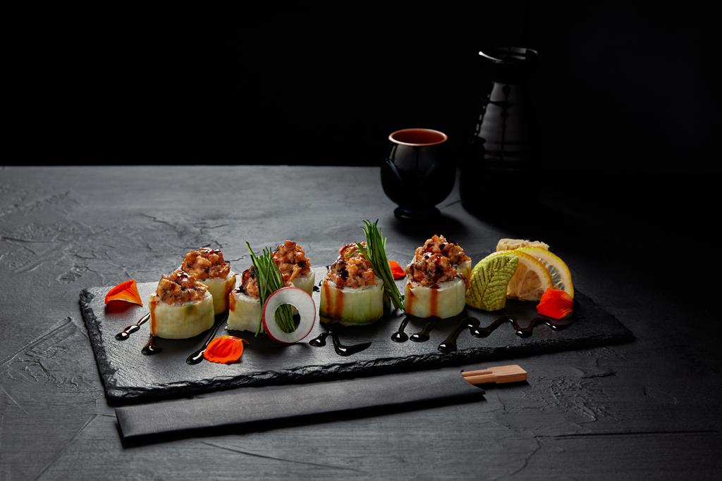 Gourmet-Sushi-Rolle mit cremigem Aal und Kimchi-Mayonnaise auf Schiefertafel und Essstäbchen   - Foto, Bild